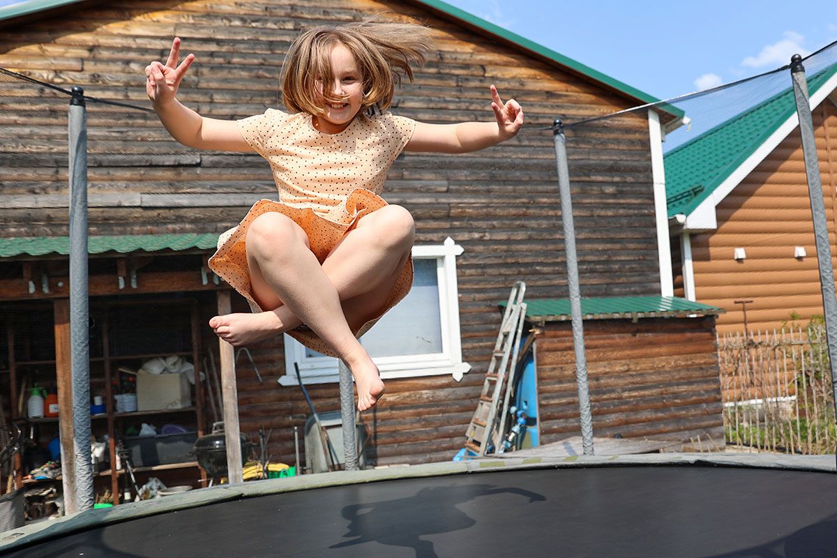 Mädchen springt auf Gartentrampolin