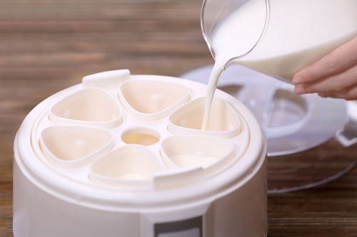 Milch wird in Joghurt-Maker gegossen