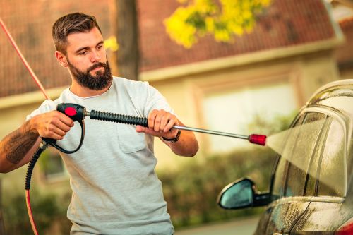 mann reinigt auto mit einem hochdruckreiniger