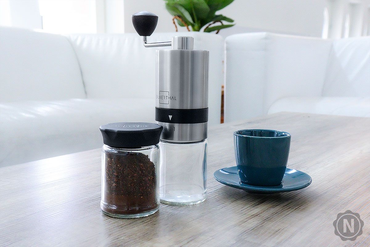 Kaffeemühle mit Glas und Espressotasse auf Tisch