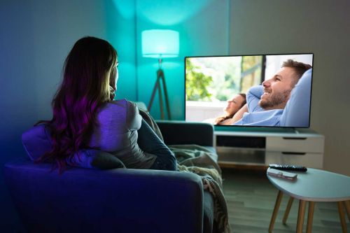 Frau sitzt auf Sofa schaut Fernseh