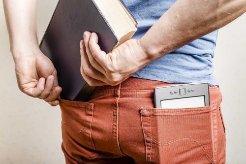 mann mit ebook-reader in der hosentasche versucht richtiges buch einzustecken