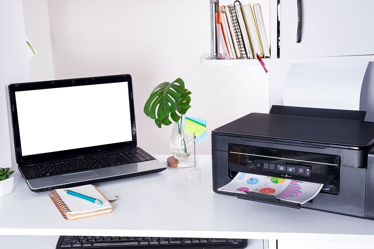 ein nicht-mobiler Drucker steht auf dem Schreibtisch neben einem Laptop