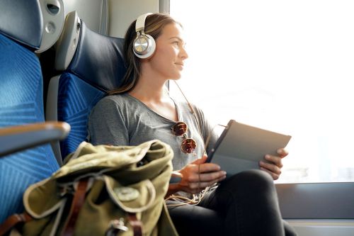 junge Frau sitzt im Zug und hört Musik