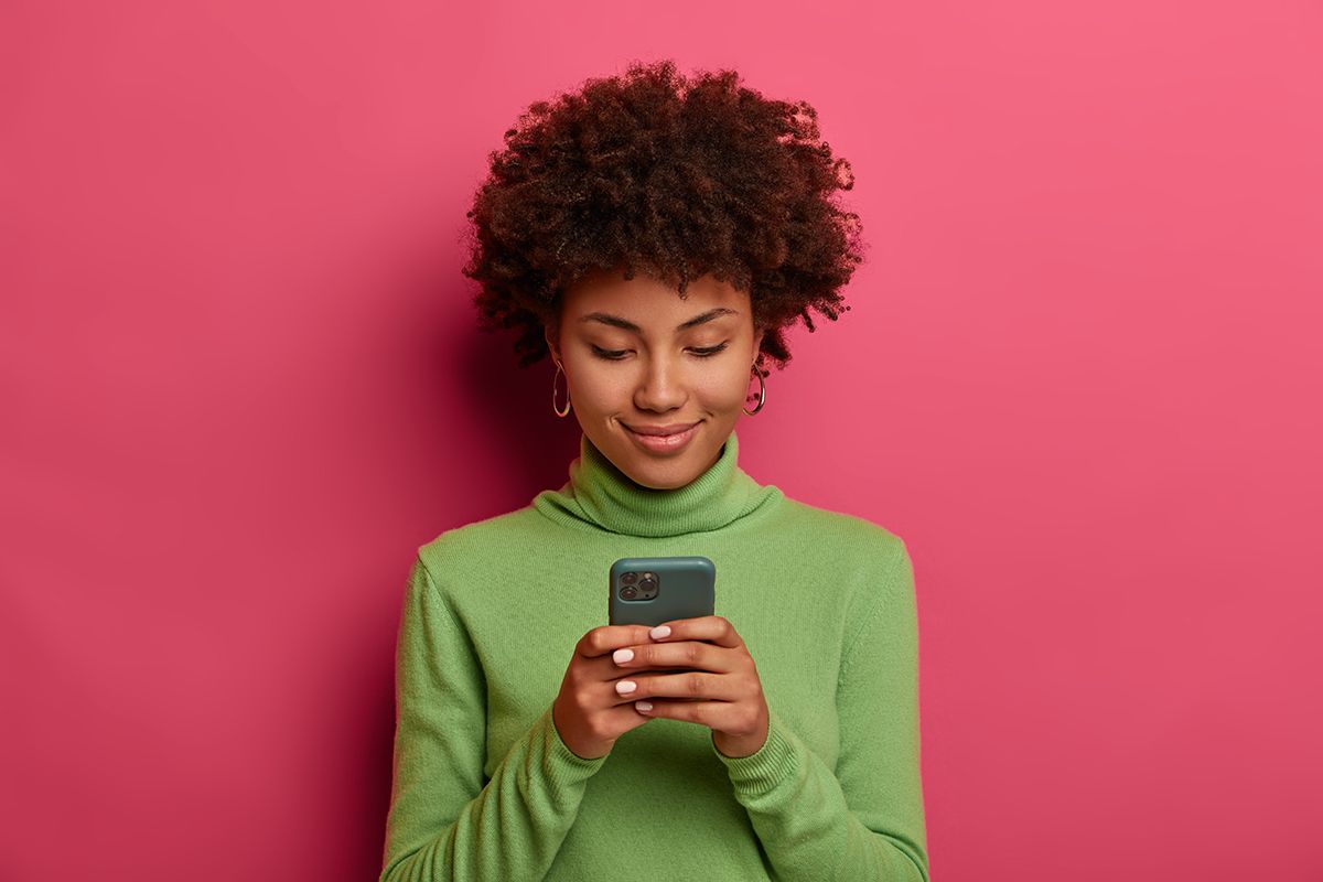 junge Frau mit Smartphone in der Hand vor pinker Wank