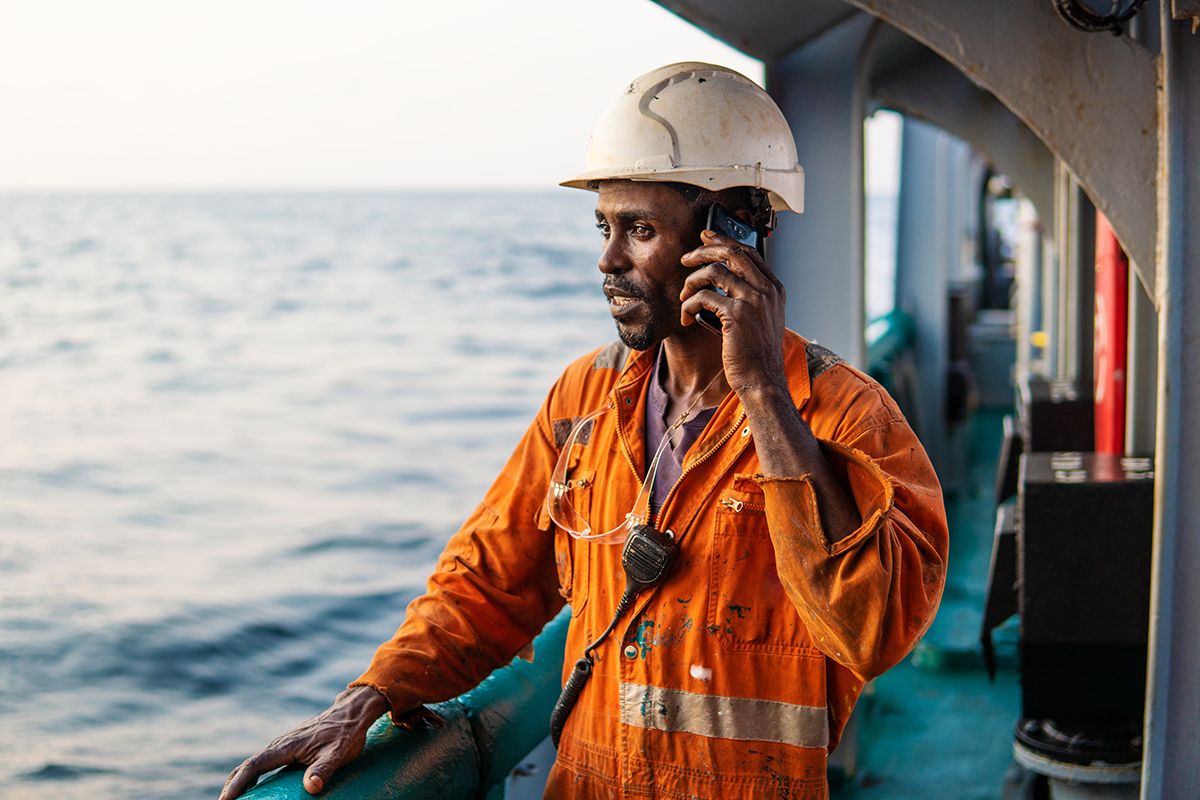 Person auf einem Frachtschiff nutzt ein Smartphone