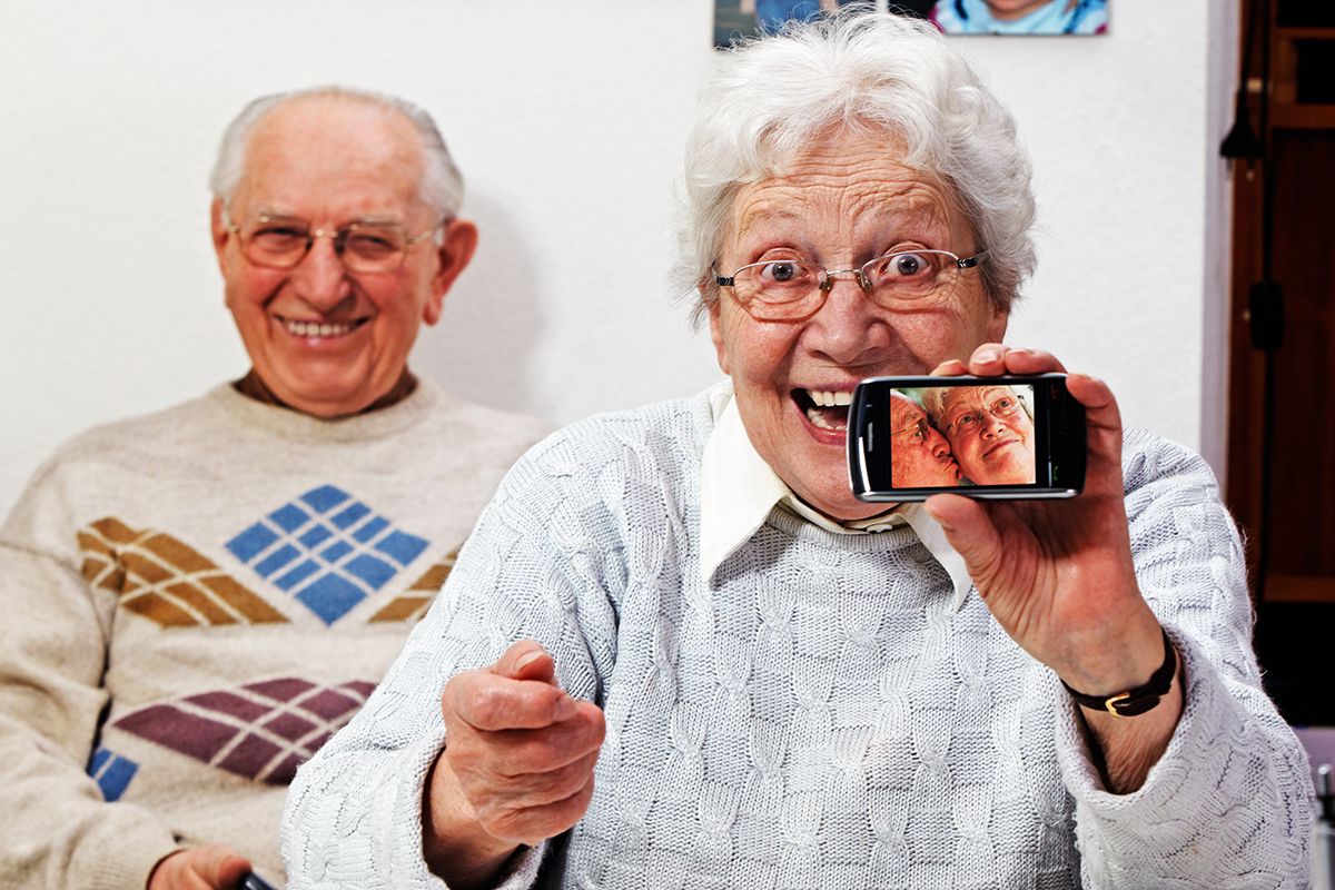 zwei aeltere Personen freuen sich bei Verwendung von Smartphone