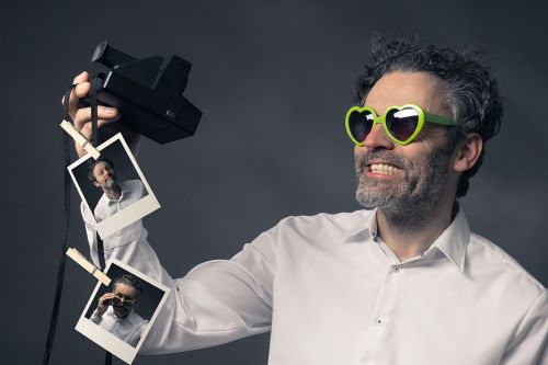Mann mit Sofortbildkamera macht Selfies