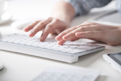 Hände beim Tippen auf weißer Tastatur
