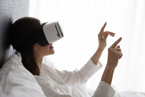 Frau im Bett benutzt VR-Brille