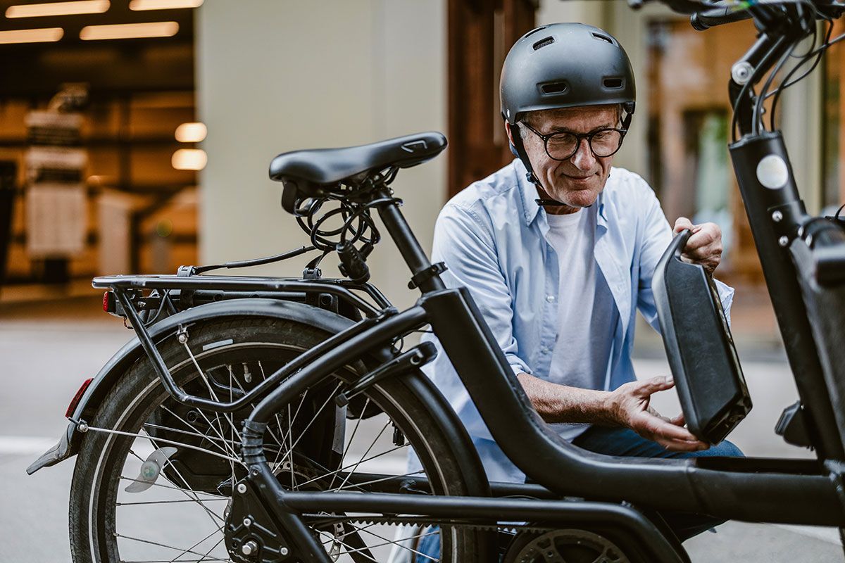 Mann mit Helm setzt Akku bei Herren-E-Bike ein.