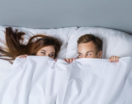 Sexbeziehung - Mann und Frau unter einer Bettdecke