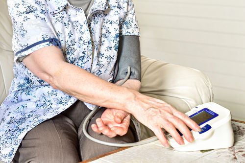 ältere Frau nutzt Oberarm-Blutdruckmessgerät