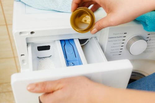 Frau füllt Weichspüler in Waschmaschine