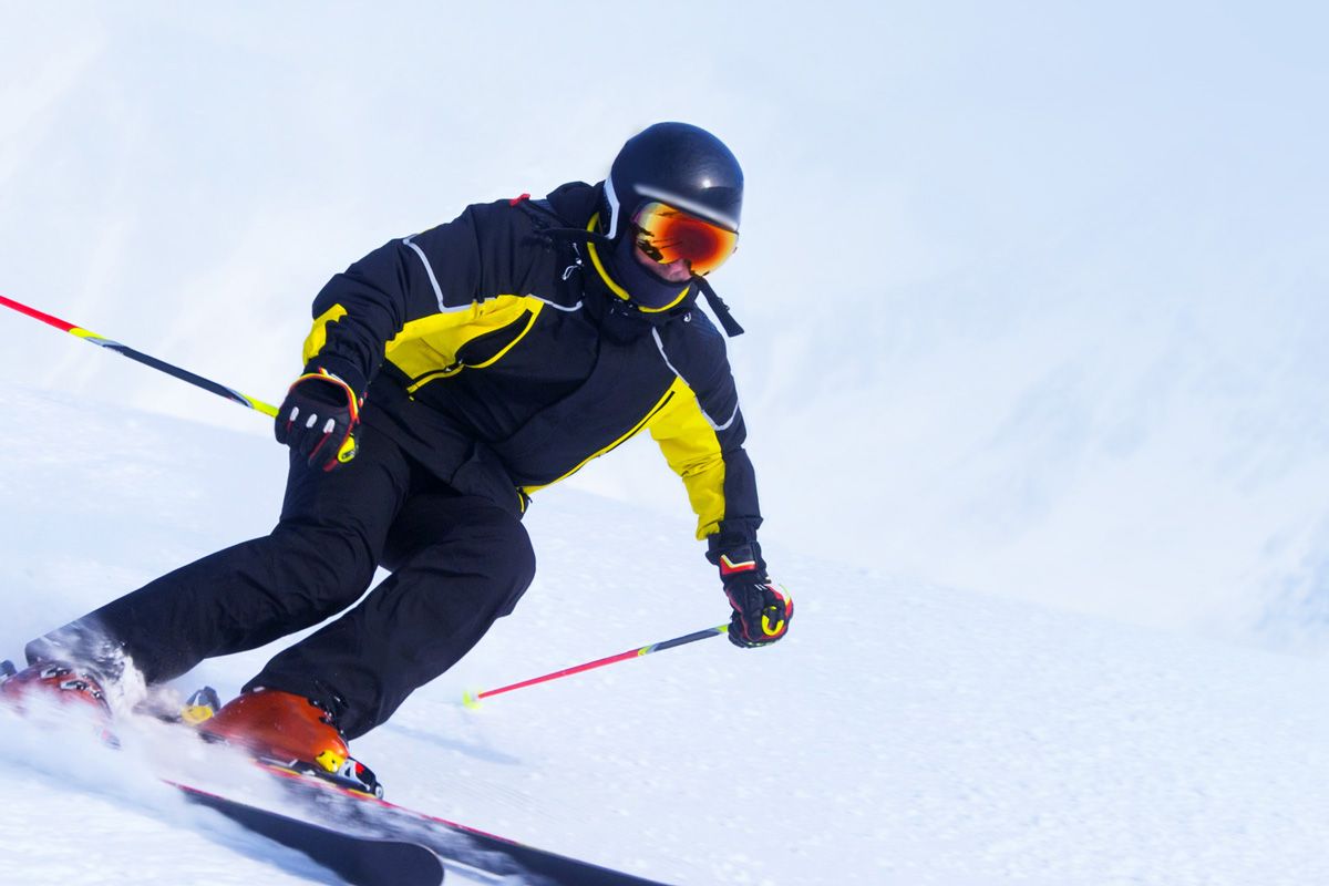 Person mit Helm faehrt Ski