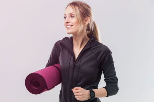 Frau im Trainingsanzug mit Yogamatte