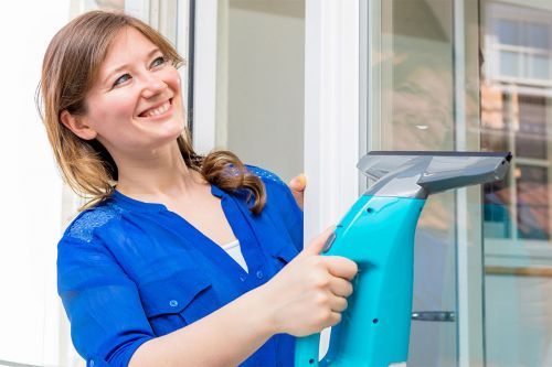 Frau putzt Fenster mit Fenstersauger