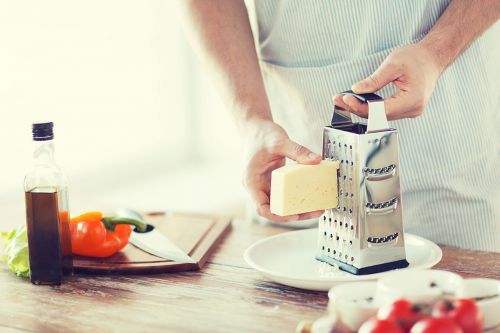 Mann in Küche reibt Käse