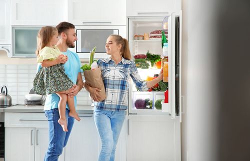 Eltern mit Kleinkind vor Kühlschrank