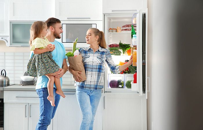 Familie steht vor Kühlschrank