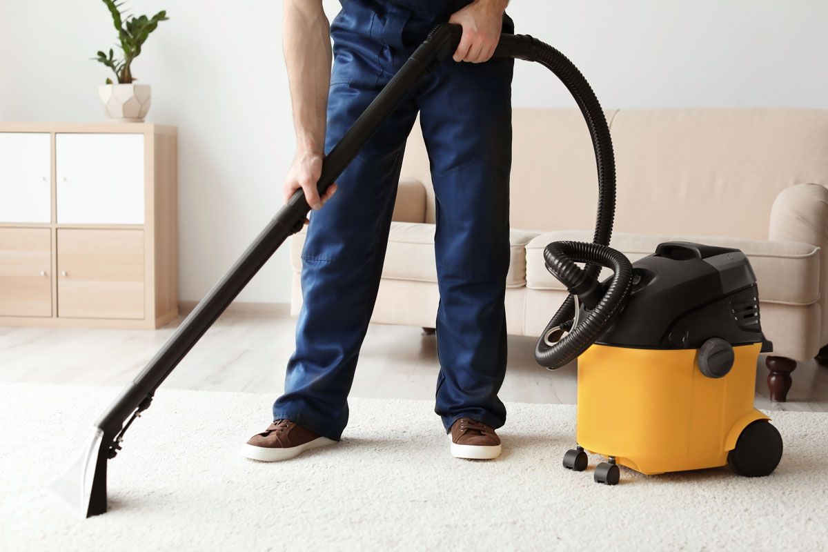 Mann saugt Teppich in Wohnzimmer