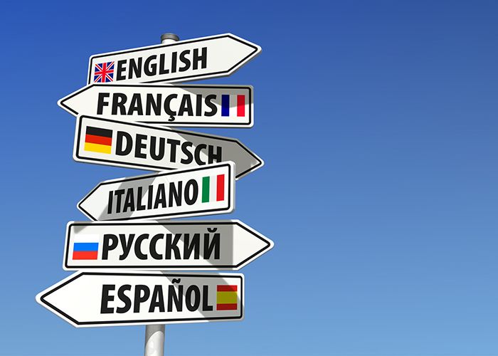 Online Sprachkurse - Hinweisschilder mit verschiedenen Sprachen zeigen in unterschiedliche Richtungen