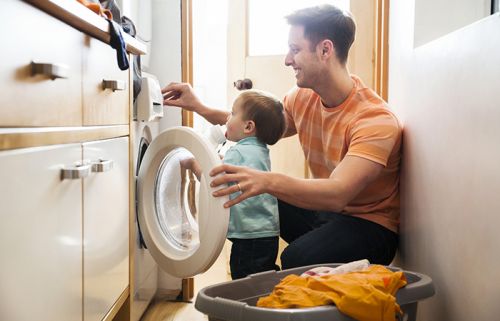 Vater und Sohn bedienen Waschmaschine