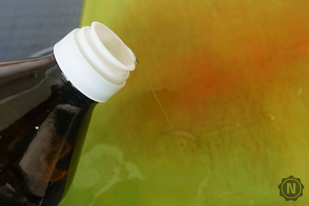 Speiseöl wird aus Flasche auf grünes Brett geträufelt