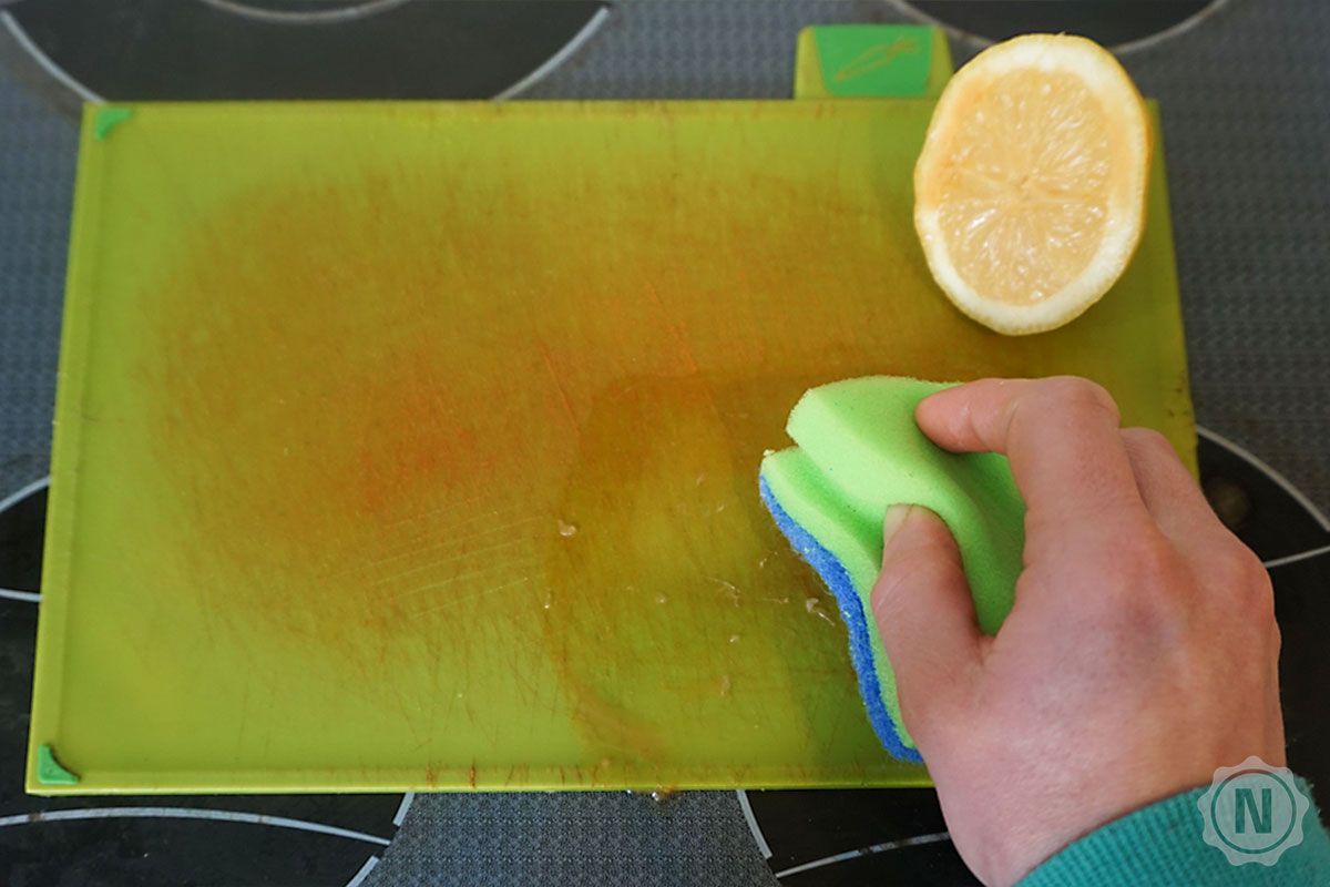 Zitronensaft wird mit grünem Schwamm auf Brett verrieben