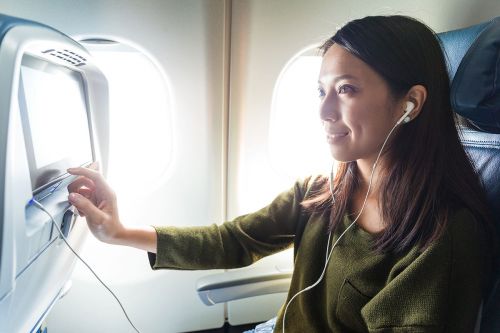 Frau mit Kopfhoerern im Flugzeug