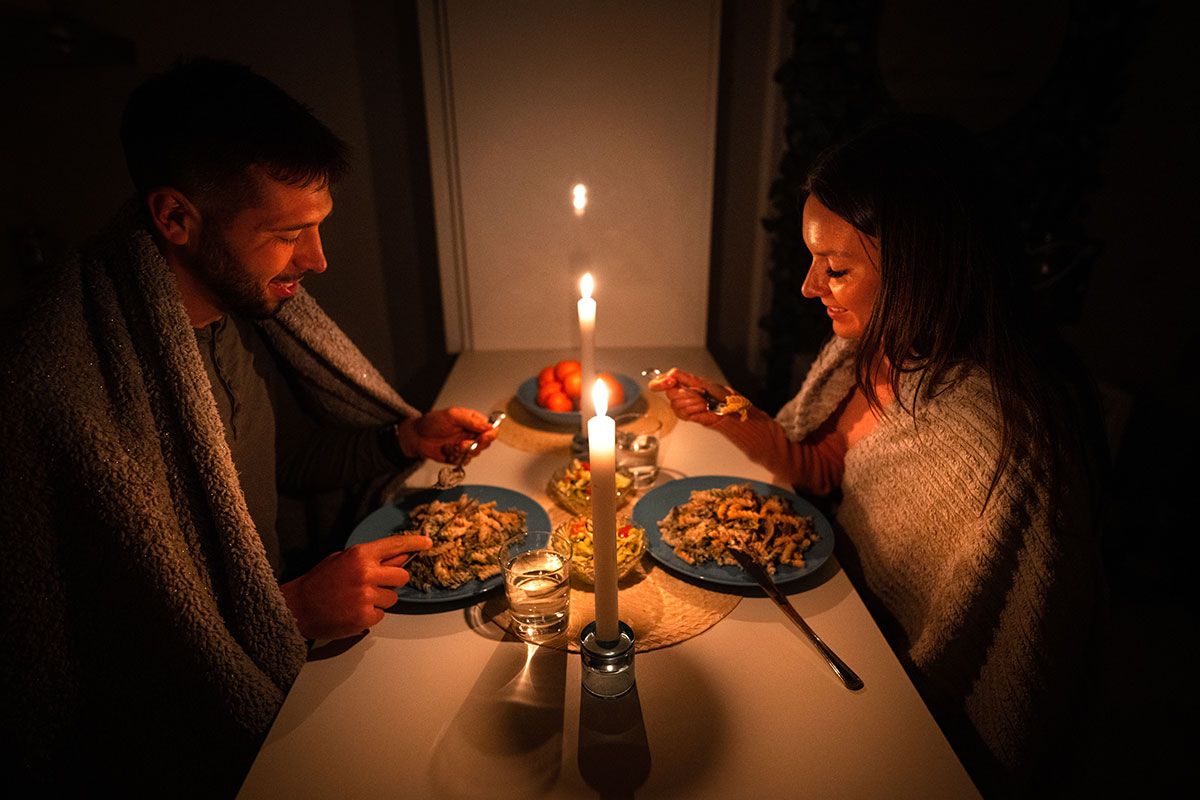 Ein Paar isst Nudeln bei Kerzenlicht waehrend eines Stromausfalls